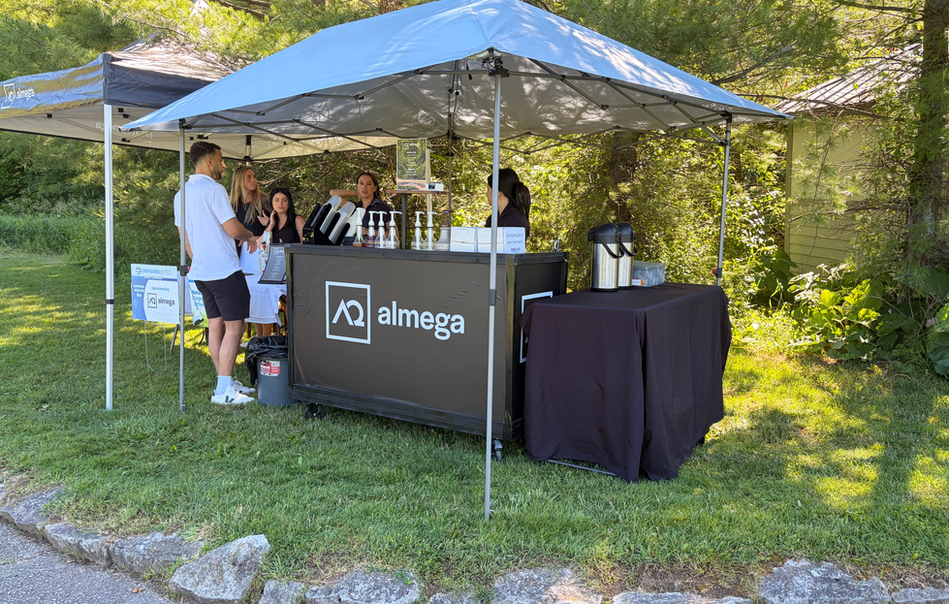 Almega outdoor event booth under a blue tent Canopy