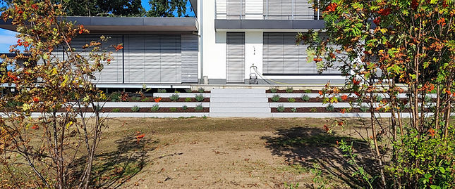 Modernes weißes Haus mit Rollos, Treppe und fertigem Garten.