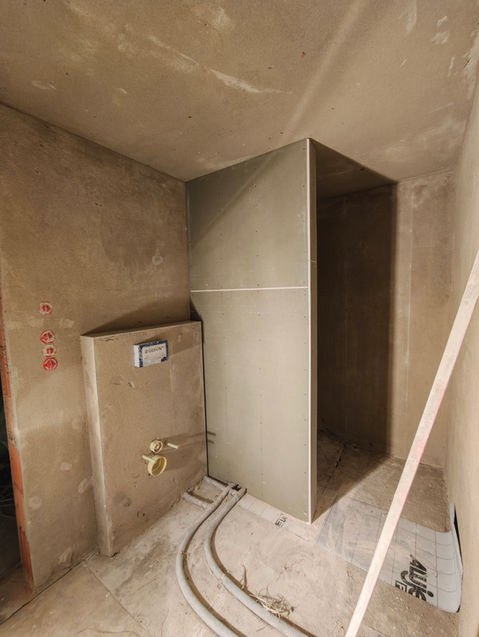 Unfertiges Badezimmer mit Duschkabinen- und WC-Rahmen, Trockenbau Installation.