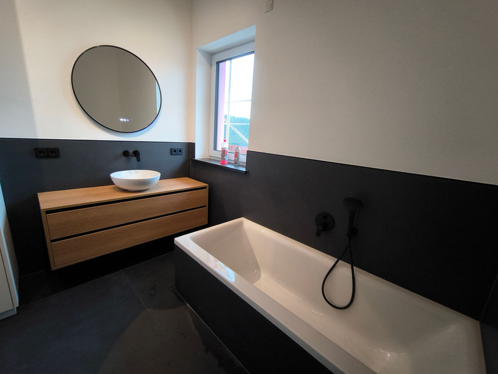 Modernes Bad, Badsanierung (schwarzes Design), Badewanne, Holzwaschtisch, ovaler Spiegel.