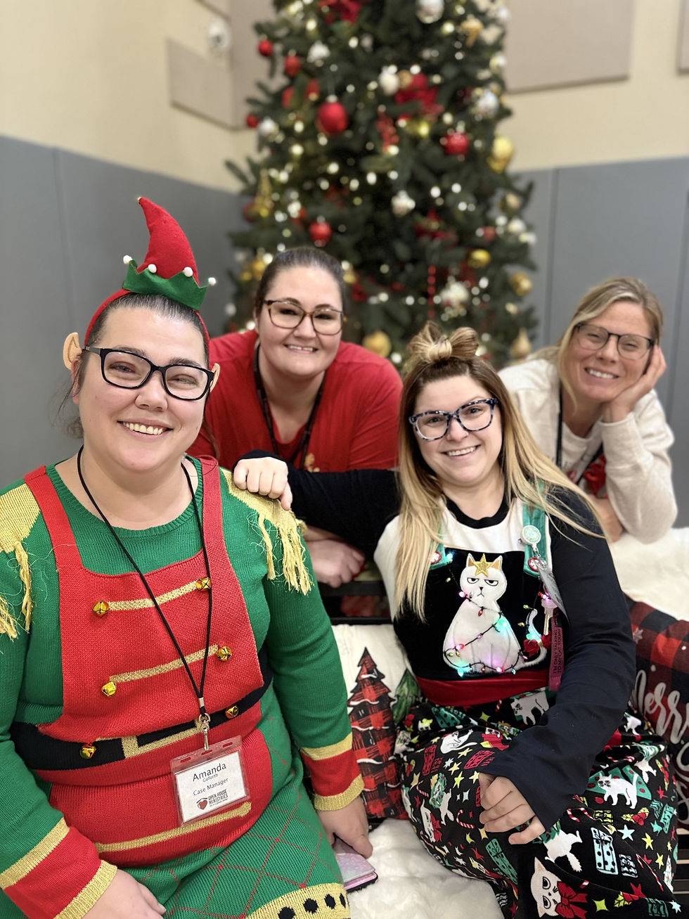 Four women in festive Christmas clothing by tree