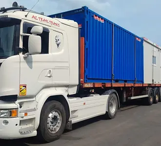 Un camion trak trans équipé d'un plateau droit, lui même équipé de twist locks afin de pouvoir transporter des conteneurs. Ici, le véhicule transporte 2 conteneurs de 20 pieds.
