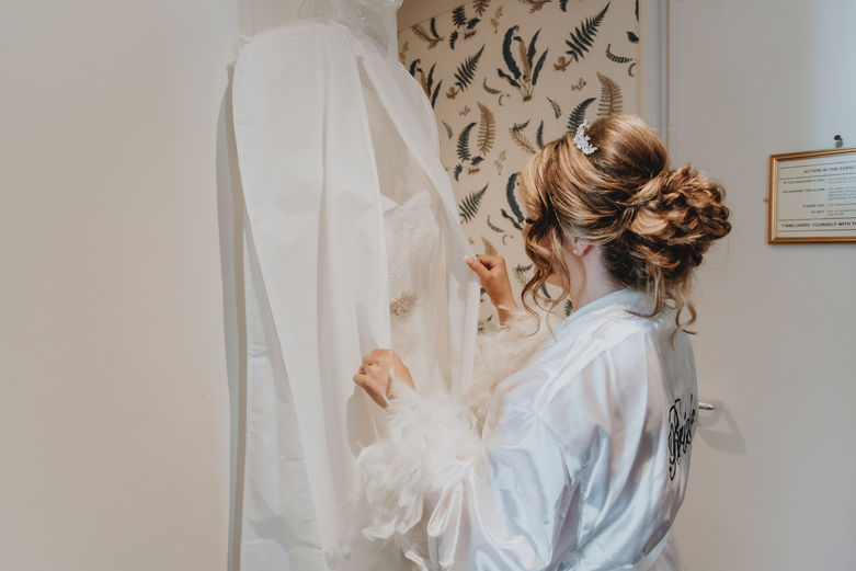 hung wedding dress with bride holding it