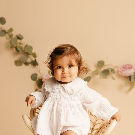 Séance photo bébé en studio à Bonnut (Landes), enfant assis sur petite chaise bohème dans une ambiance naturelle.
