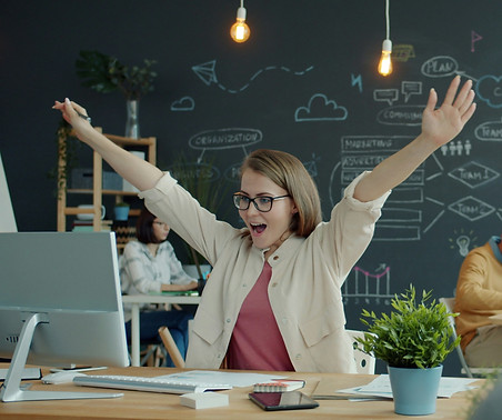 Happy young woman is celebrating business achievement looking at computer screen getting g