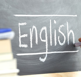Hand writing on a blackboard in an language class with the word "English" wrote in. Some b