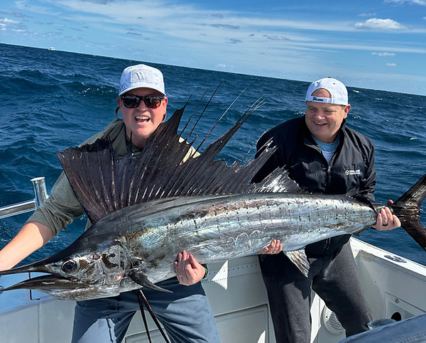 2 men holding up a large sailfish