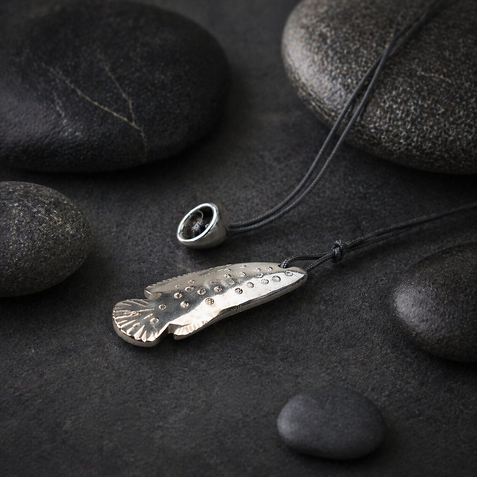 Handmade silver fish pendant featuring textured details on the metal surface, suspended on an adjustable black cord.