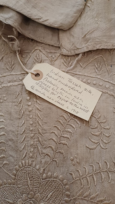 detail of a piece of textile from South Asia with a accessioning tag and collection number