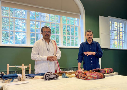 two people standing around a table with some objects from the South East Asian Textiles collection in the act of illustrating the objects