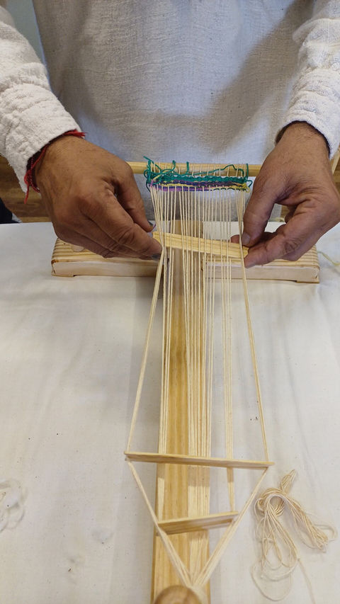 detail of hands in the act of weaving a piece of cloth on a loom