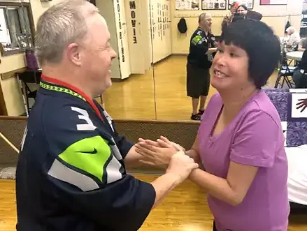 Two people with developmental disabilities holding hands and smiling.
