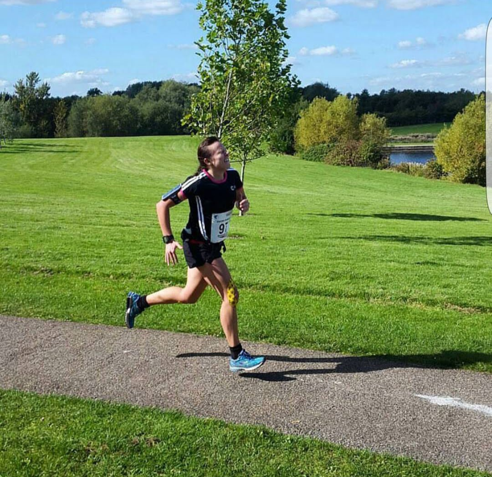 Emma O'Toole running, looking like she is stuggling with tape on her right knee. Caught in the rigmarole of injury