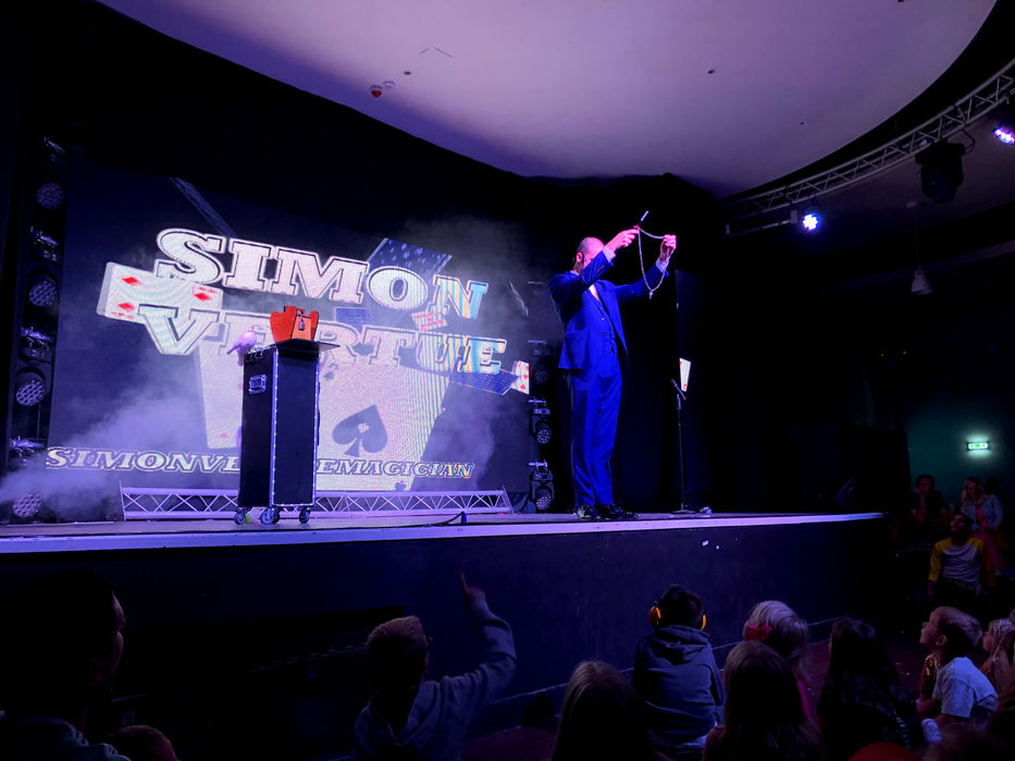 Magician Simon Vertue performing magic on stage.