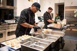Chef in black uniform plating food in a kitchen