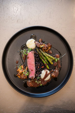 Plated medium-rare steak with asparagus and purée