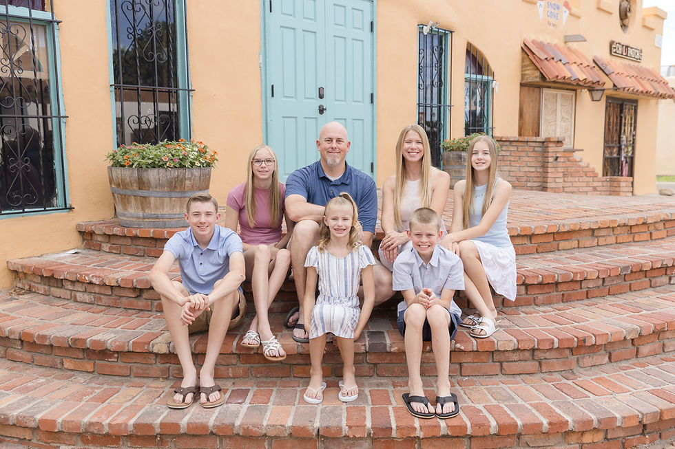 family of seven sitting on steps in front of a turquoise door in old town