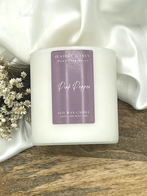 A Malton Brown Pink Pepper Dupe candle in a matte white vessel with purple label.