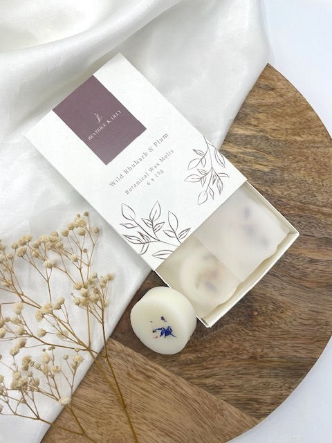 6 round shaped wax melts with dried botanicals on them in a luxury match style box. In the scent Wild Rhubarb & Plum.