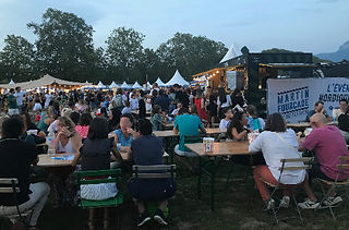 People sit at wooden tables at the Martin Fourcade Nordic Festival.
