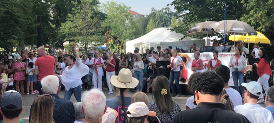 A couple dancing the tango surrounded by people watching, outside.
