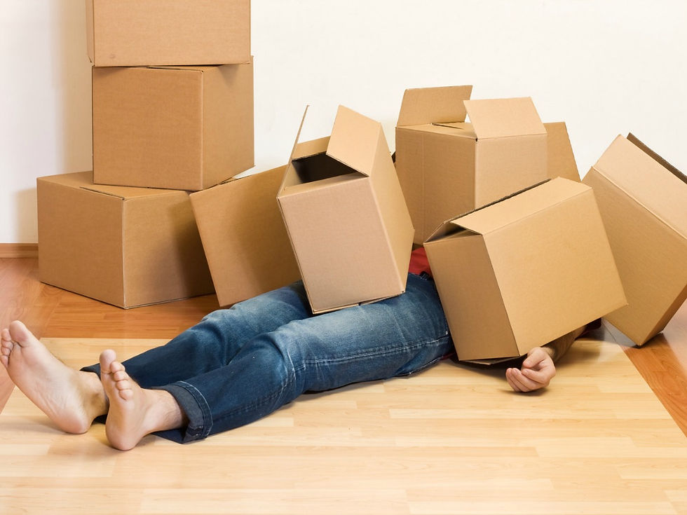 Photo of a woman lieing on a floor covered in moving boxes. You can't see her upper body only her legs and bare feet.