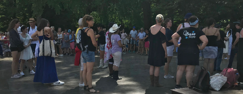 People in threes are in a circle about to do some American 'line dancing'.