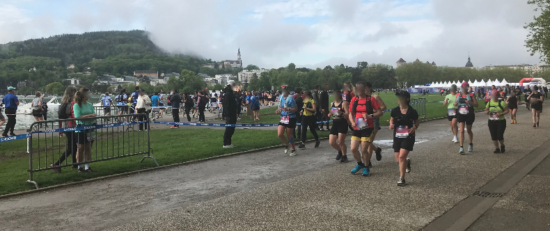 Some runners are running away from the Paquier, at Annecy marathon. The church of the Visitation can be seen on a hilltop in the background.
