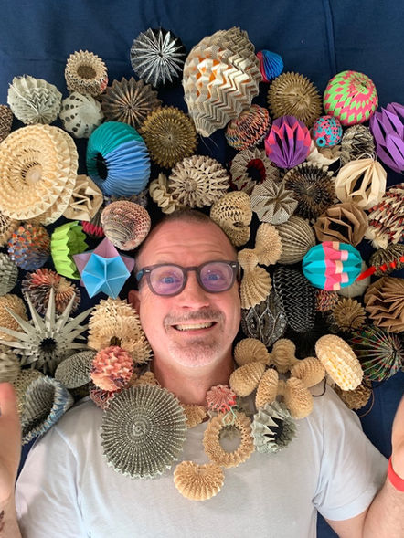 A handsome man surrounded by thousands of baubles.