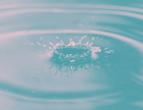 a droplet splash makes waves on the surface of blue liquid