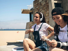 two girls by the beach listening to music on their phone