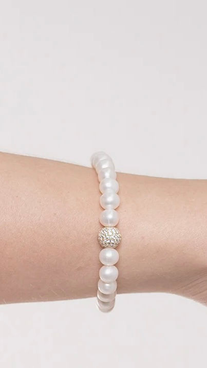 EIN SÜßWASSERPERLENARMBAND MIT GLITZERKUGEL AM HANDGELENK
