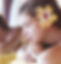 Woman lying on massage table with head resting on hand and eyes closed wth flower in hair
