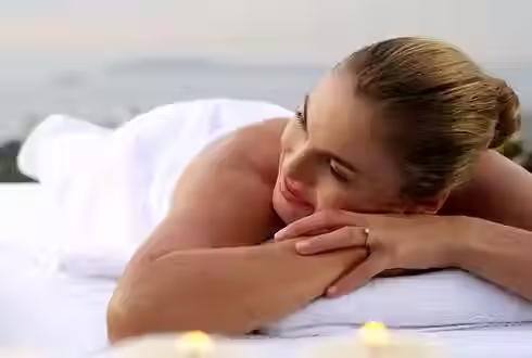 Woman smiling at man while having a relaxation massage with white towels