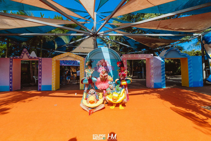 שחקנים בתלבושות ססגוניות ודמויות שטח באירוע חברה מעוצב של חברת SAP. השחקנים לובשים תחפושות צבעוניות הכוללות אלמנטים של פירות וצורות גיאומטריות תחת צילייה גדולה בשטח פתוח.