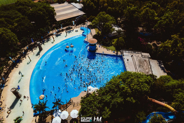 צילום אווירי של פארק מים רחב ידיים עם בריכה כחולה גדולה, מוקף במדשאות ירוקות, עצים ומתקני נופש, מתוך גלריית אירועים של חגי מגידו הפקות