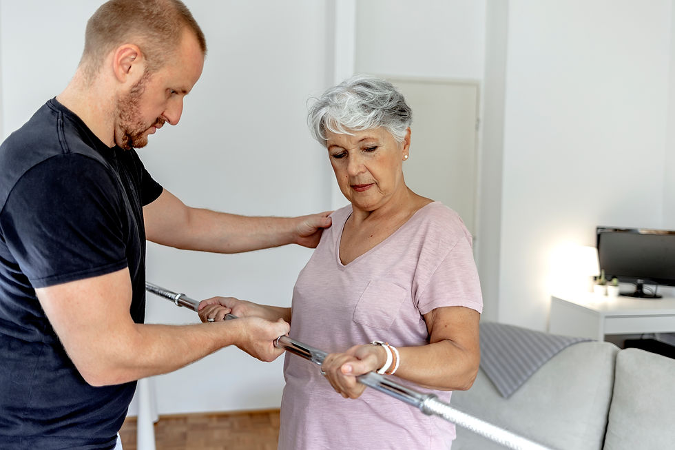Male nurse helps senior woman walk along metal walking bars for physical therapy