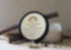Side view of a jar of salve with the lid leaning against the jar to show the ingredient list.