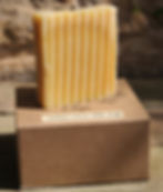 Pale yellow bar of soap on a kraft box.