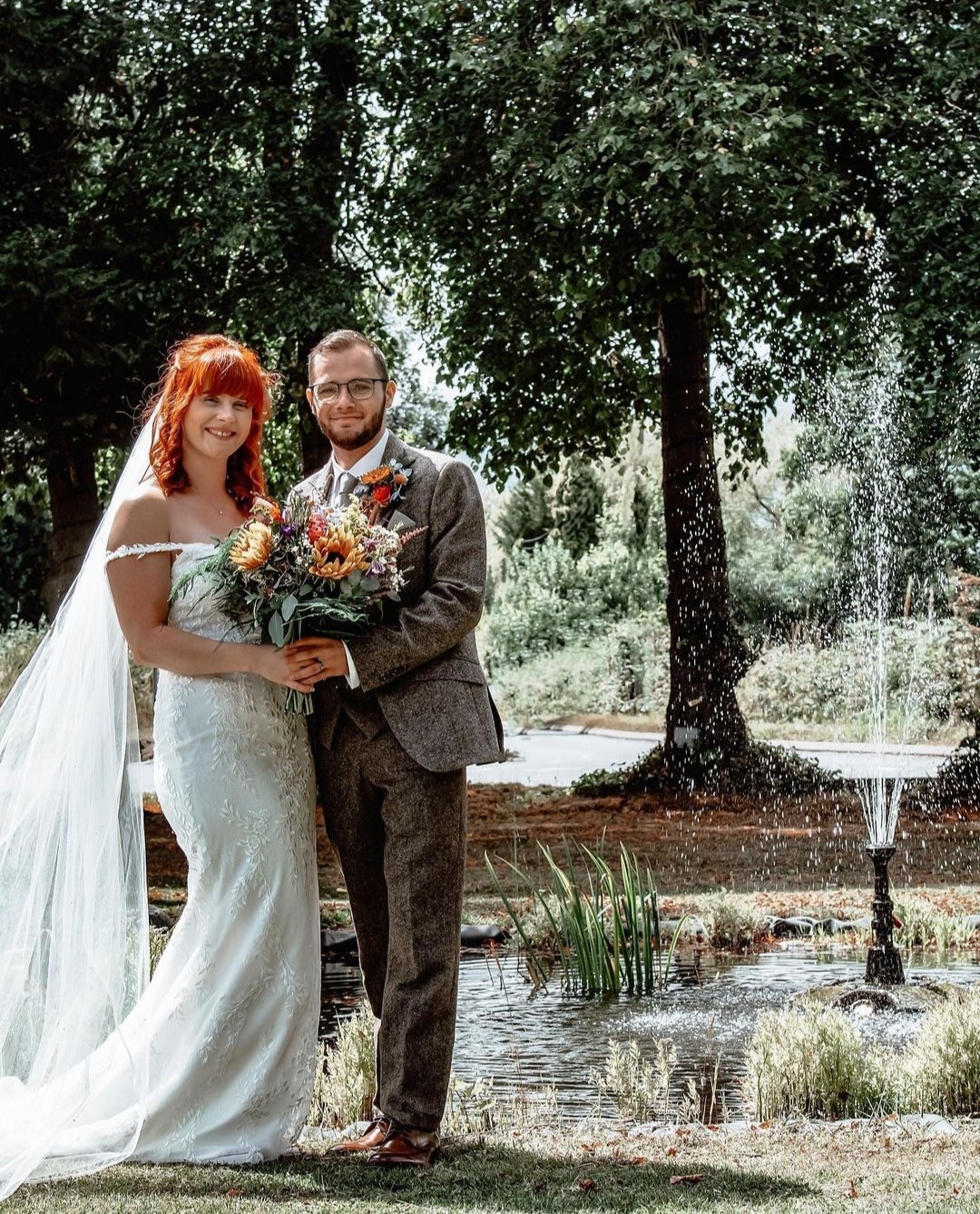 Happy wedding couple poses by a fountain