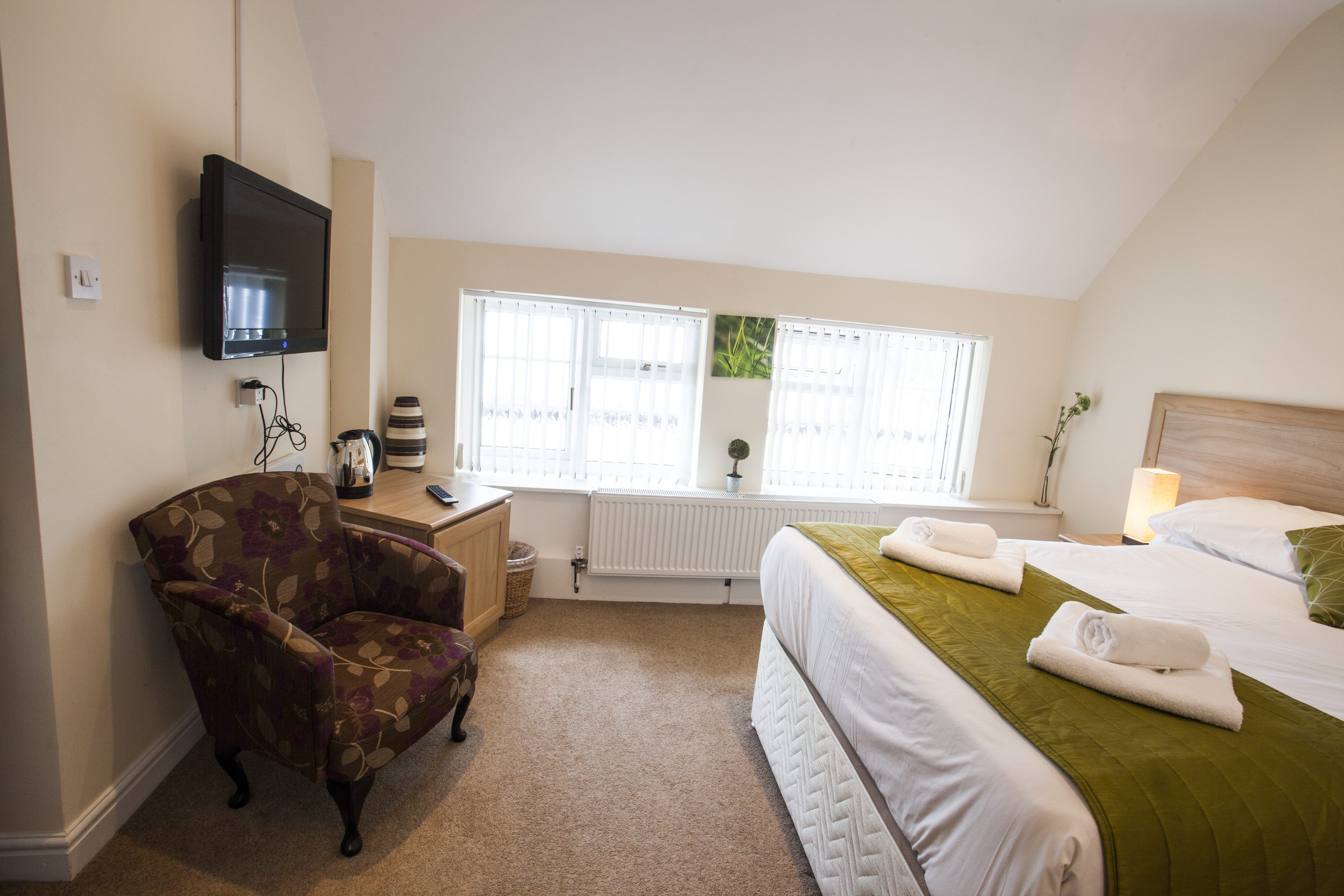 Comfortable double room with TV, armchair, and large windows