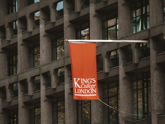 Grey building exterior displaying an orange 'Kings College London' banner.