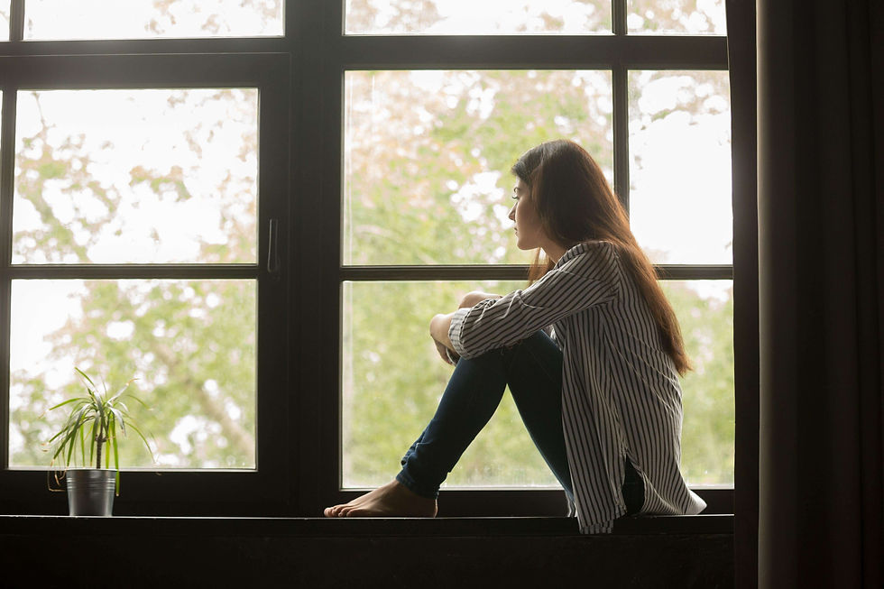 Femme regardant par la fenêtre, plongée dans ses pensées, illustrant l'anxiété et les inquiétudes du quotidien.
