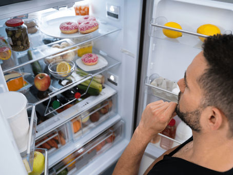 Homme ouvrant le réfrigérateur de manière automatique, illustrant le grignotage émotionnel ou les compulsions alimentaires