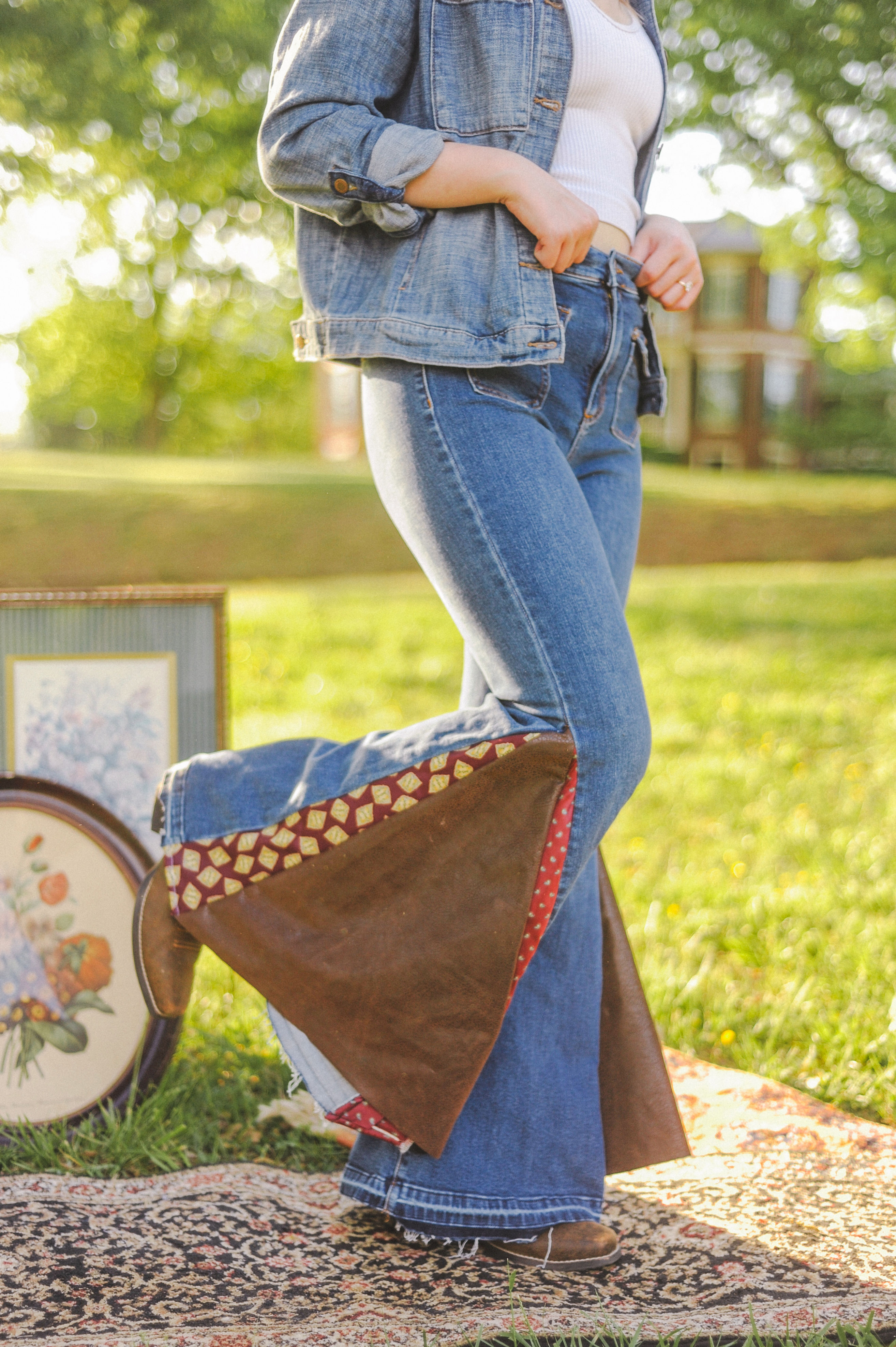 A pair of high-rise flare jeans made from upcycled Alter'd State denim, featuring repurposed neckties sewn along the sides. T