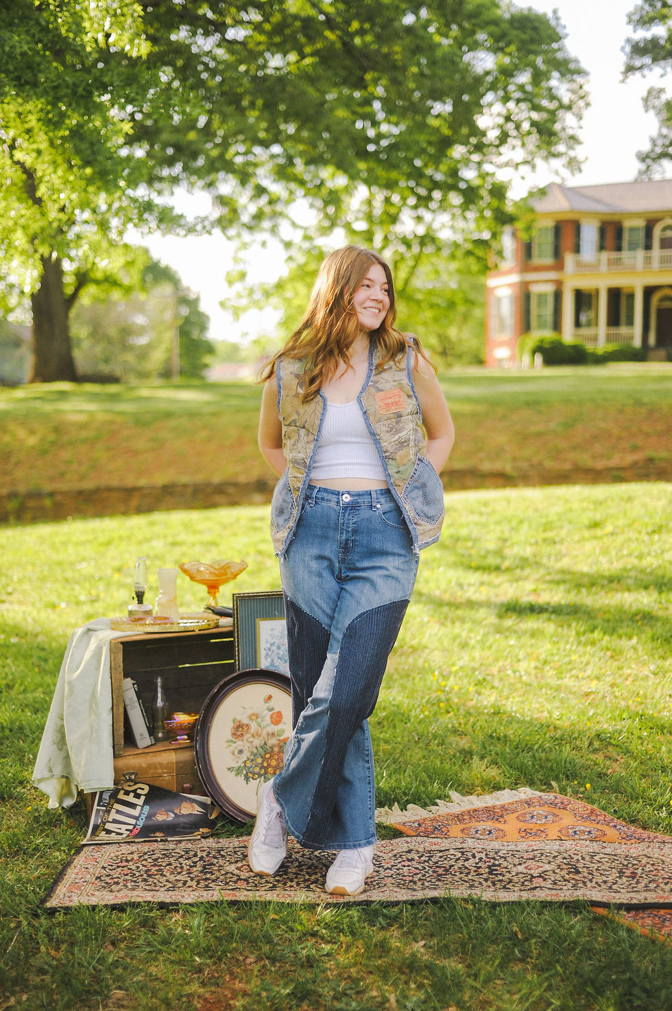Thumbnail: A woman stands barefoot on a vintage rug outside, wearing high-waisted flared jeans with dark blue corduroy inserts on the le