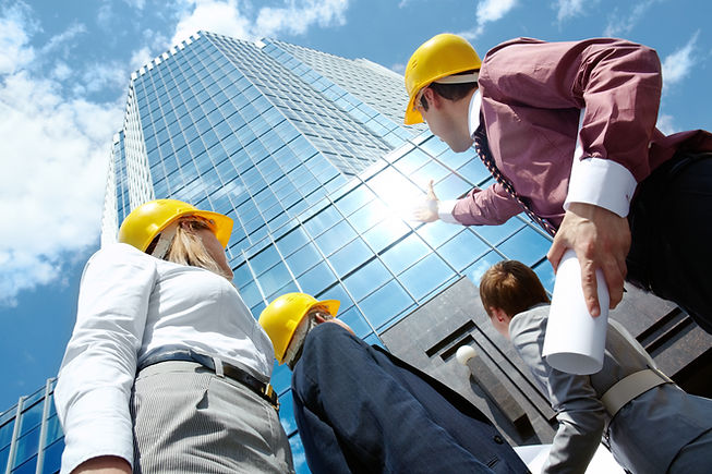 below-view-of-business-partners-in-helmets-looking-at-modern-office-building-against-c-SBI