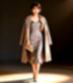 A petite woman models a versatile light brown wool coat, styled formally with pants and elegantly with a slip dress.