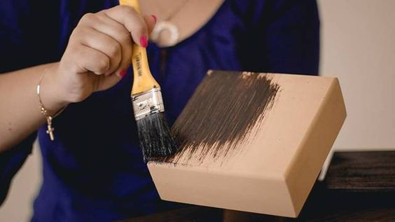 mãos femininas aplicando verniz em uma caixa de MDF