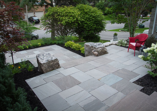 Detail of porcelain paver joints transitioning to planting bed with sedge, boxwood and mulch for a crisp yet natural front yard look